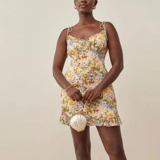 Woman wearing a floral dress holding a shell against a plain background